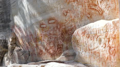 aboriginal rock art showing paintings of boomerangs, hands, feet, stone axes, shields, nets and an assortment of animal tracks