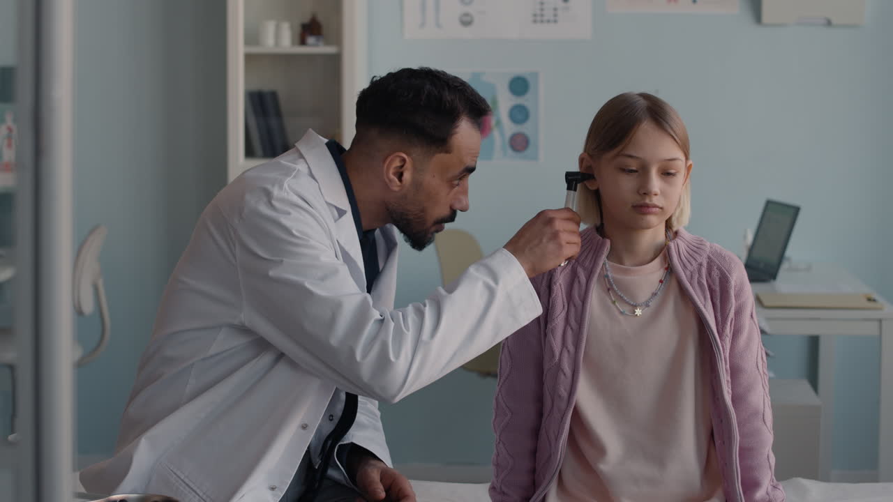 Doctor examining a child's ear with an otoscope