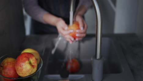 una mujer lava una jugosa manzana roja bajo un grifo 2