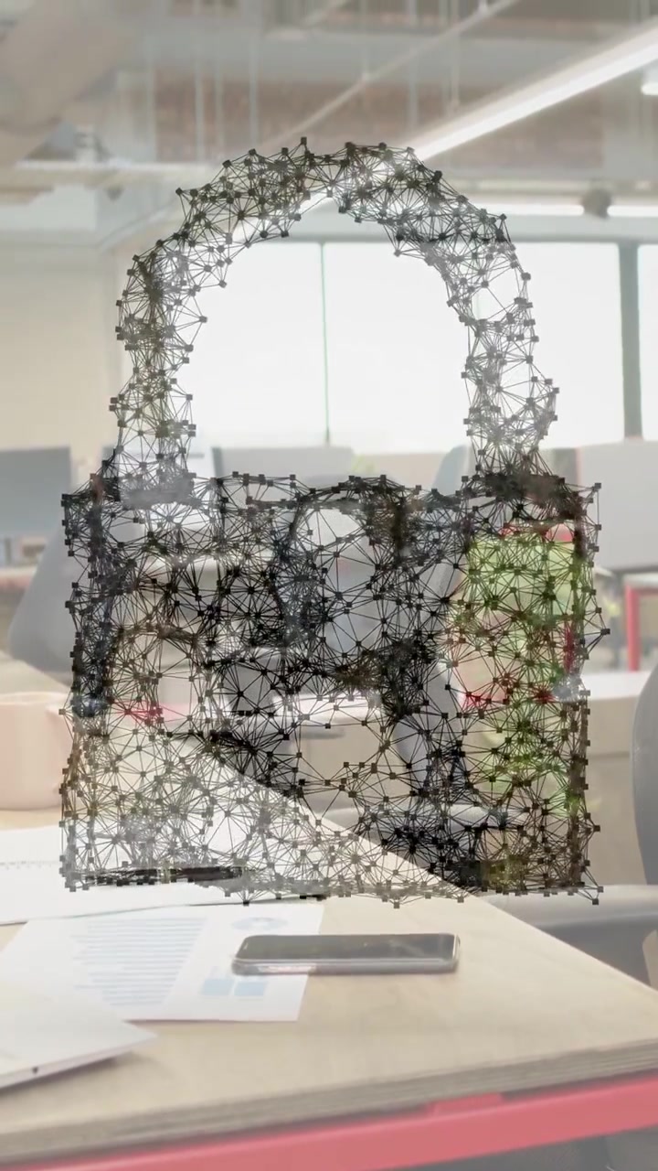 Video verticale: Costruzione di un lucchetto 3D in wireframe che si forma sopra una scrivania dopo una scansione, poi esplode per rivelare la scrivania.