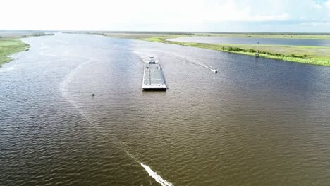 A-Tugboat-Guides-a-Barge-Down-the-Apalachicola-River-to-the-Apalachicola-Bay-in-Apalachicola,-Florida