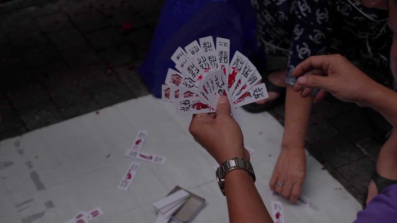 Mani di persone giocano al gioco di carte Tam Cúc in Vietnam, primo piano, al rallentatore