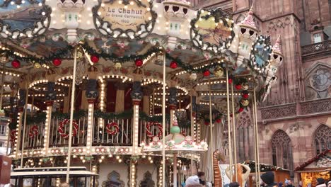 festive carousel spinning around in front of the strasbourg cathedral at festive christmas market in strasbourg, france europe