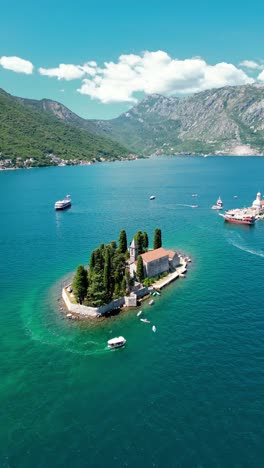 sveti dorde island - saint george monastry in the middle of the island. famous travel destination. tourist boats visiting the island. vertical aerial perspective.