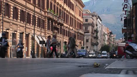 Los-Edificios-Antiguos-Se-Alinean-En-Una-Calle-Muy-Transitada-Con-Vehículos-Y-Peatones-Que-Pasan-Por-Palermo,-Italia-1