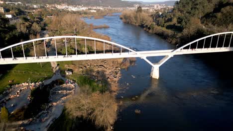 aerial shot over a bridge in the river miño in spain, great vegetation, horizon with mountains and blue sky