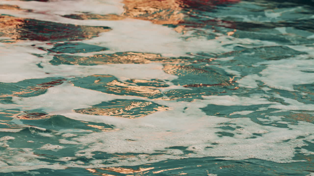 Close up of foamy sea water moving and shimmering under warm light