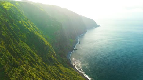 scenic towering cliffs and ocean in madeira, portugal on a foggy day - aerial drone shot