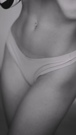 close-up grayscale image of a woman's torso and lower body, wearing underwear