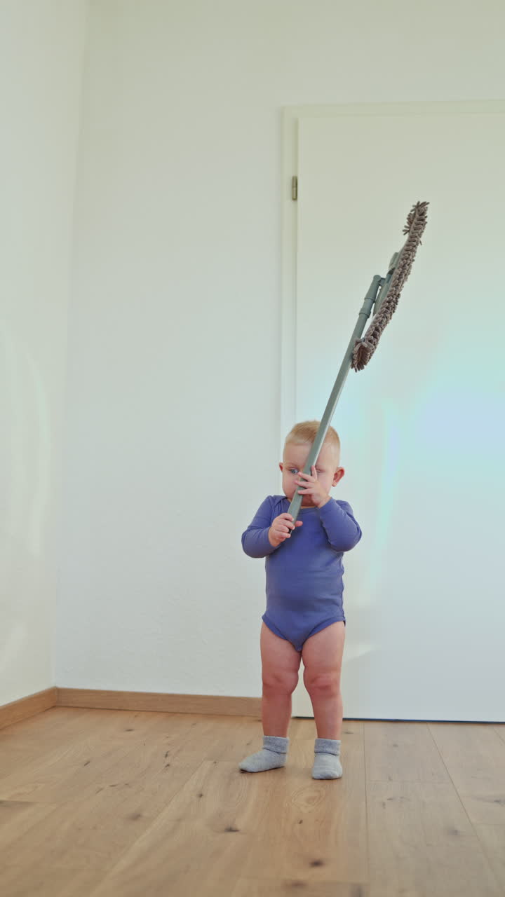 Little boy toddler washes the floor with a mop. Child helps clean the floor. Boy in a cotton bodysuit