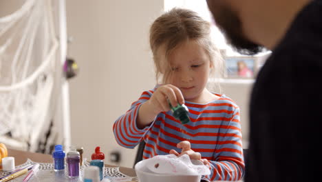 father and daughter making halloween masks at home together