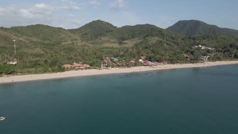 Aerial-pans-right-over-water,-revealing-long-sand-beach-on-Koh-Lanta