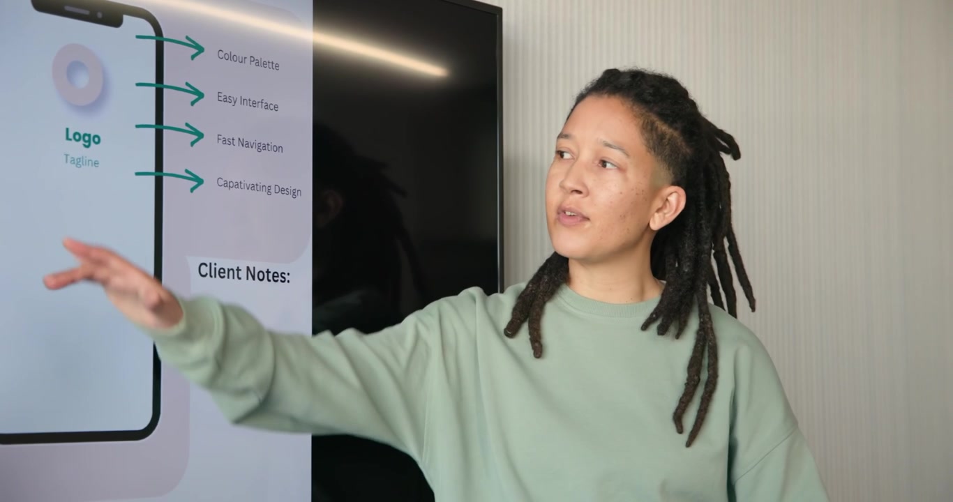 TV showing app mockup non-binary African lead wearing mint top explaining app, pointing in meeting