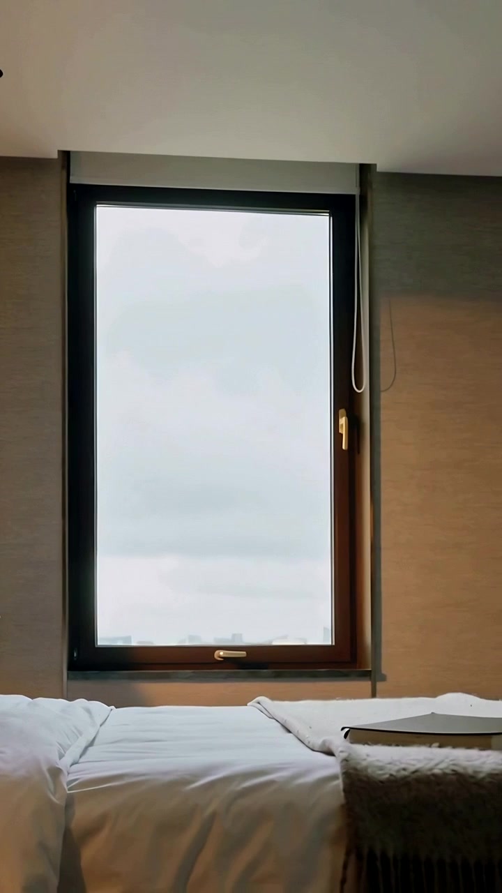 Vertical video: Pulling camera revealing tall window with handle in bedroom to reveal book on throw
