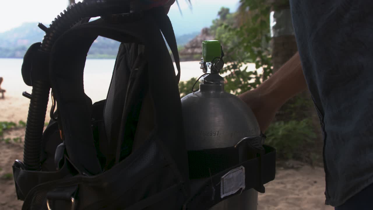 Man on an exotic beach fixing BCD on a gas bottle, Comoros islands, Moheli