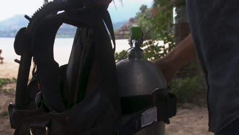man on an exotic beach fixing bcd on a gas bottle, comoros islands, moheli