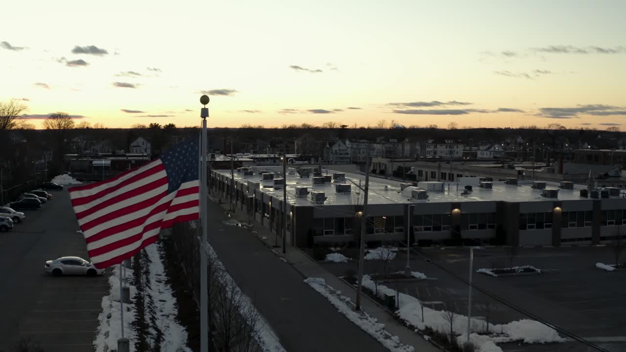 At dusk, the flag of the United States of America flaps in the gentle breeze - aerial view