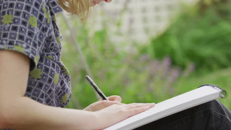 woman drawing with pen on paper outside
