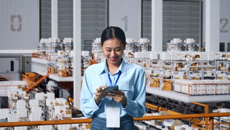 asian business woman using mobile phone in the warehouse