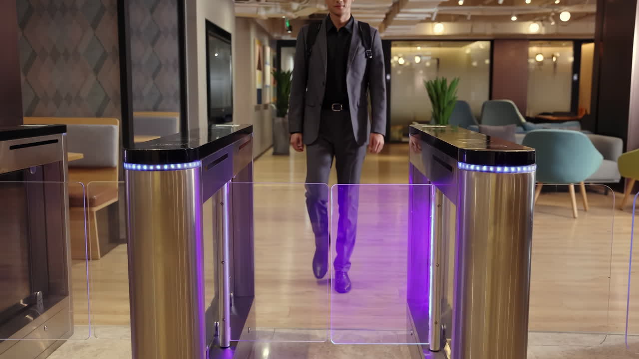 Businesspeople in a suit carrying a backpack walks out of the turnstile, employees leaving workplace finish workday with touch panel for automatic scanning and identification in modern office building