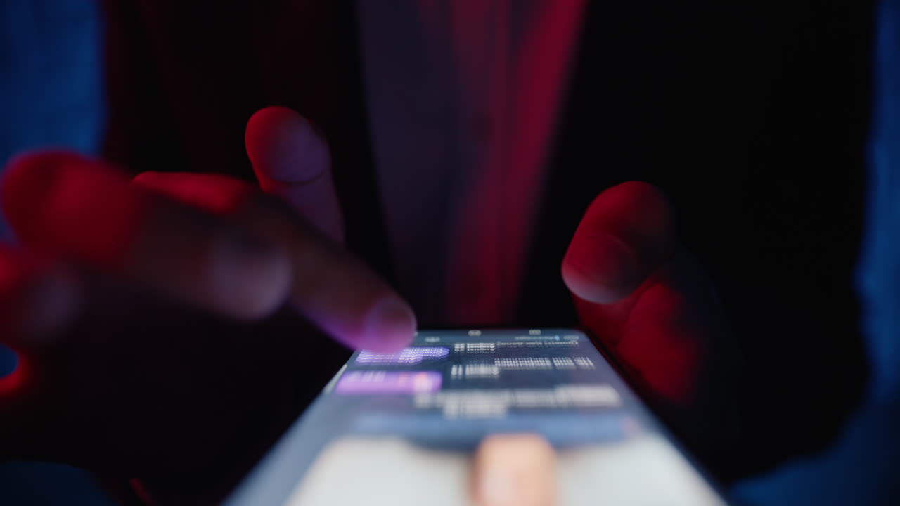 Primo piano di mani che scorrono sullo schermo di uno smartphone mentre sfogliano una conversazione in una discoteca di notte