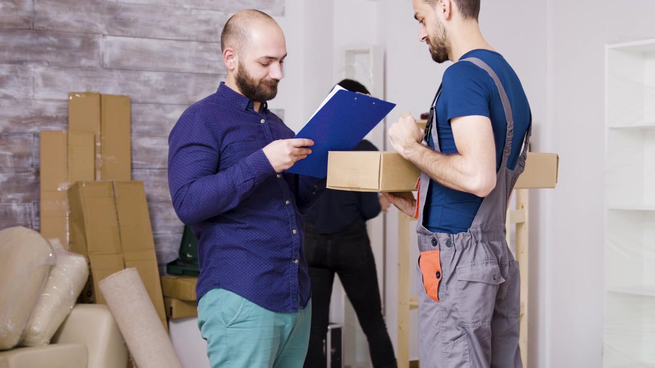 Man Receiving a Package from a Delivery Person in a New Home