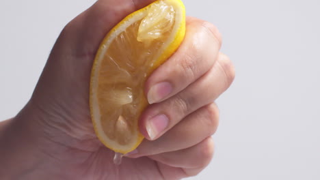 female hand squeezes fresh natural juice out of the lemon