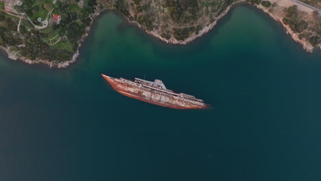 aerial rising orbit of half sunken shipwreck in elefsina, greece during sunset