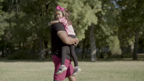 tracking shot of dad with disability carrying girl in arms