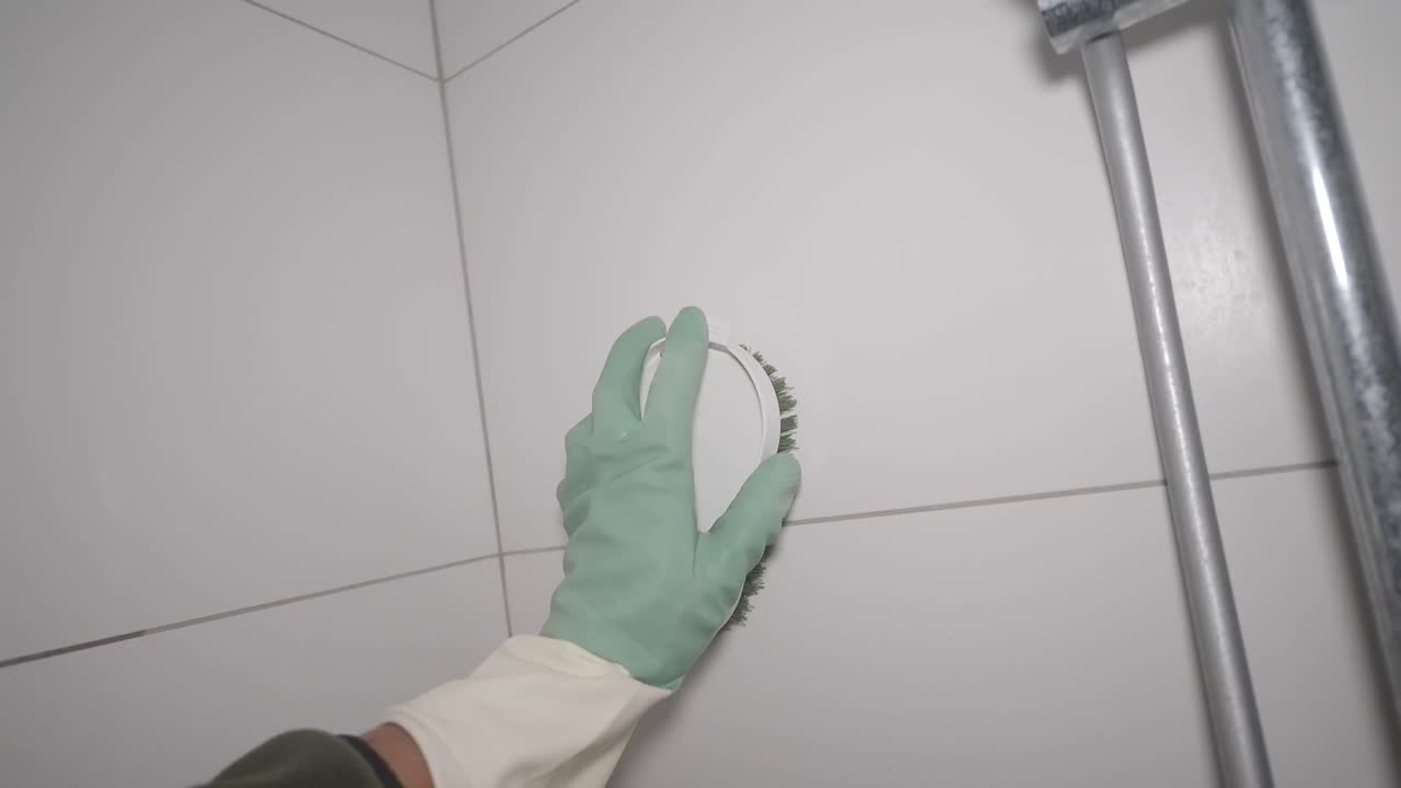 Rengøring af flisevæg med handsker