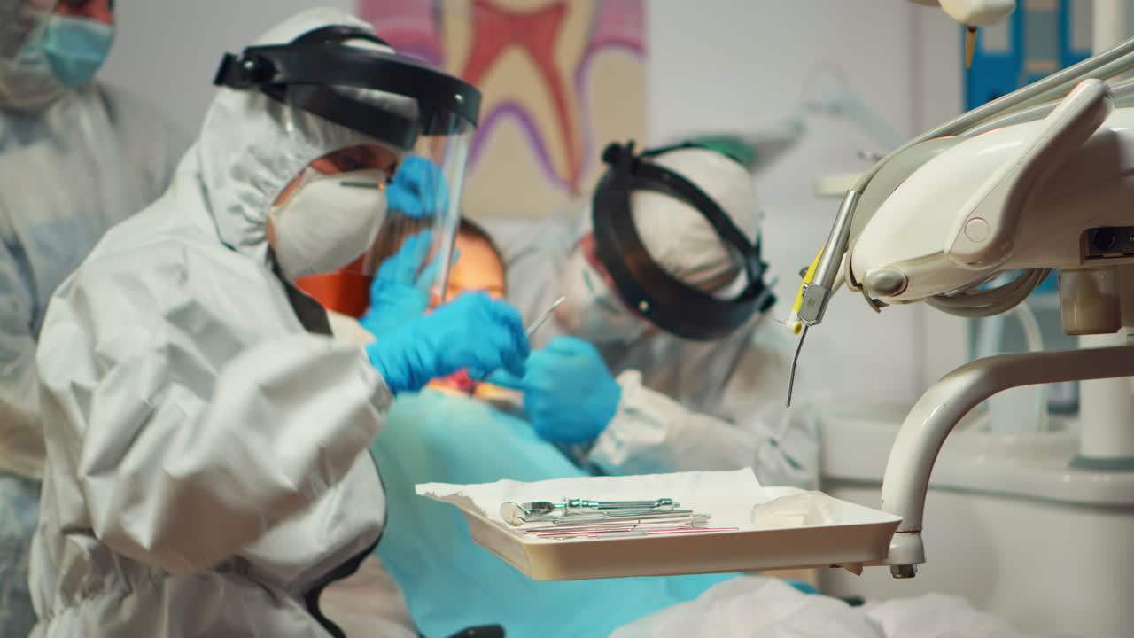 un primer plano de un médico de odontología en camiseta usando una máquina de perforación para examinar al niño