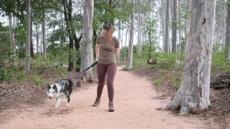 mujer se relaja en la naturaleza y pasea con su perro, respirando el aire fresco en el parque