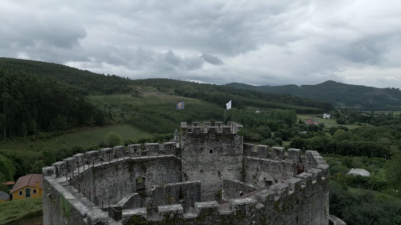 Aerial flying over Moeche Castle tower, revealing San Xurxo de Moeche parish, Spain