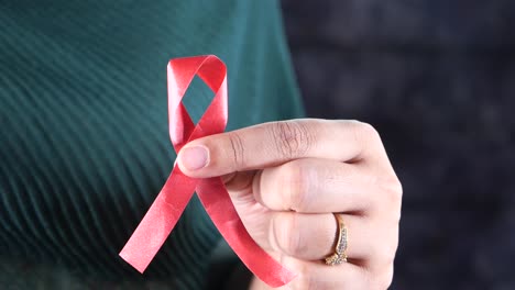 hand holding a red ribbon