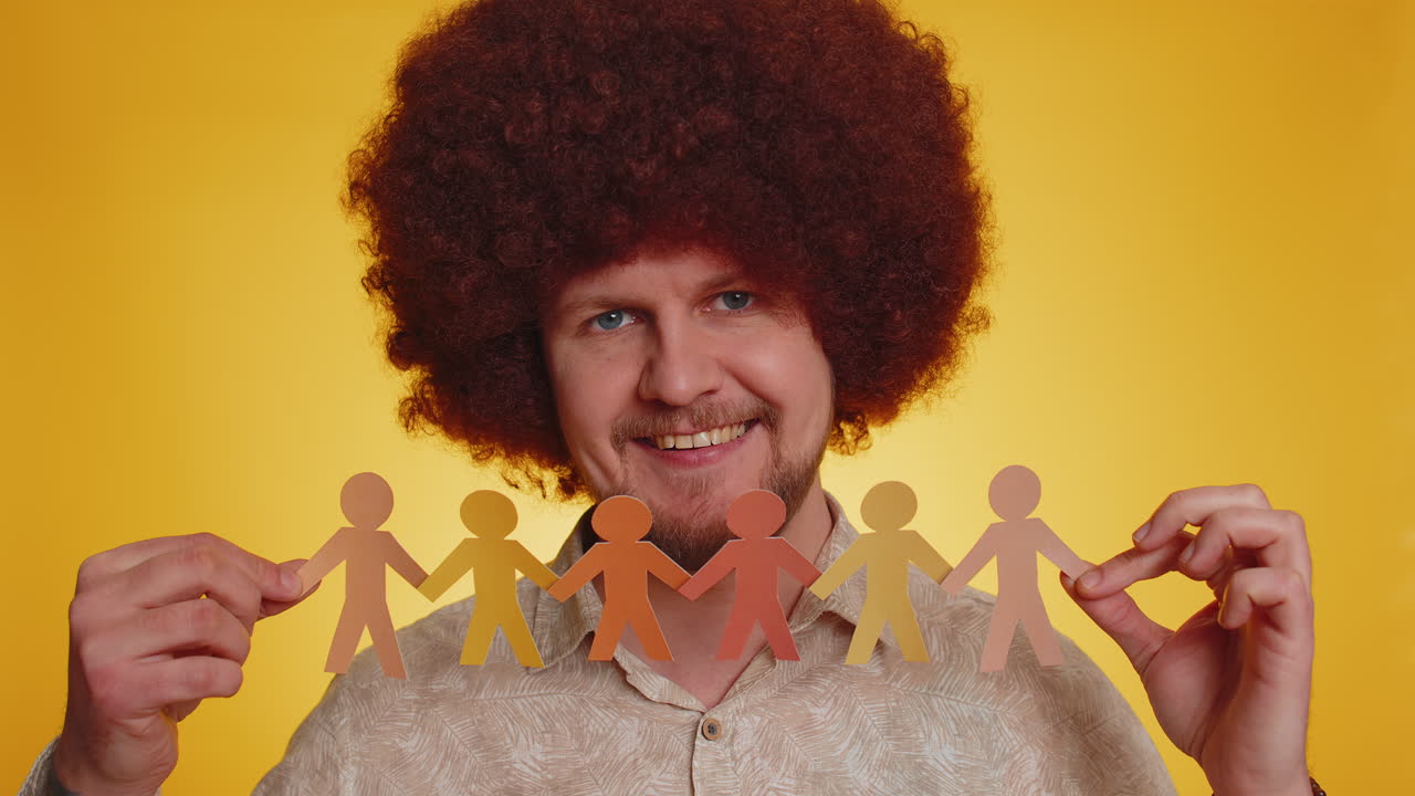 hombre con peluca afro sosteniendo una cadena de papel de personas