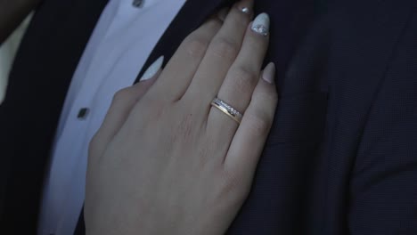 ring on the bride's hand, resting on the groom's chest