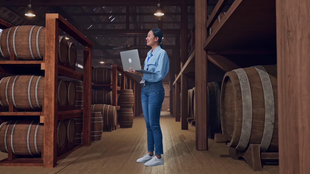 Full Body Side View Of An Asian Female Worker Standing In Cellar Of Winery, Observes By Looking Up Before She Come To Concentrating On The Laptop And Keep On Typing