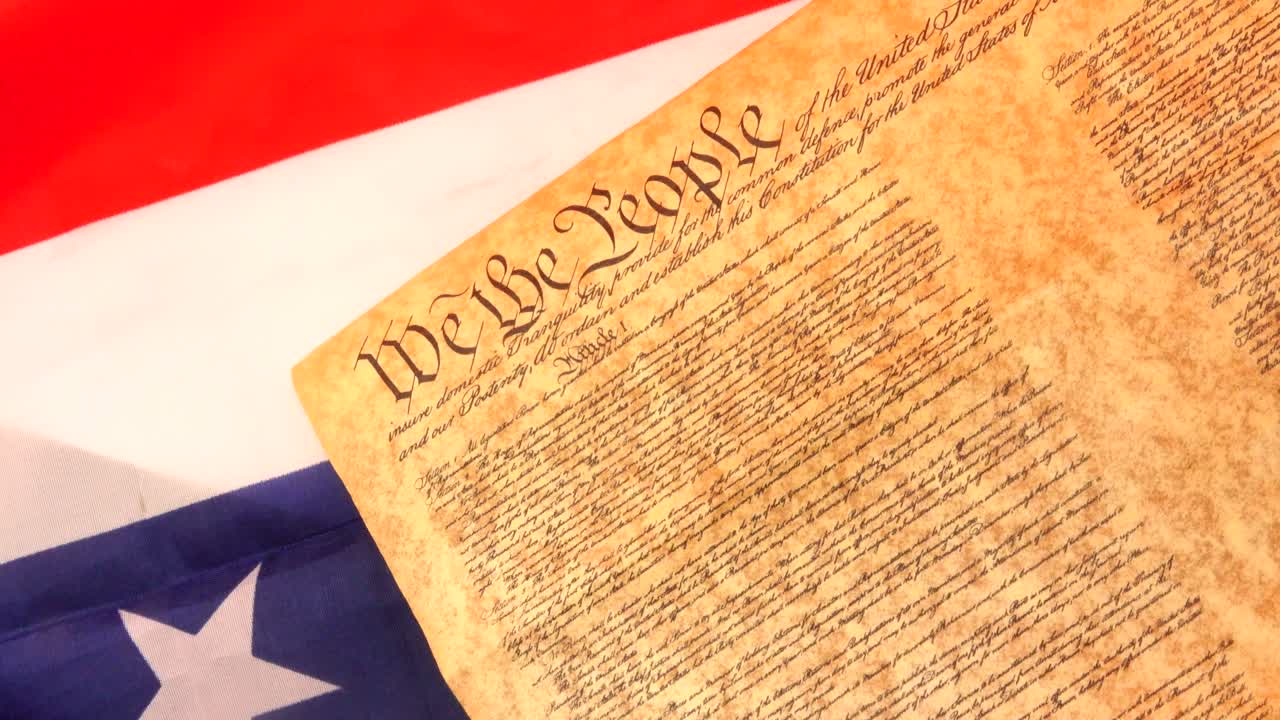 A dramatic image of the U.S. Constitution resting on a burning American flag, symbolizing protest, civil liberties, and the ongoing tension between patriotism and dissent in the fight for freedom