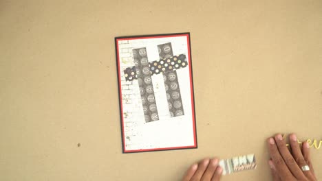 creating hashtag symbol using decorative paper for gift card project, shown overhead, hands gently place and organize layers