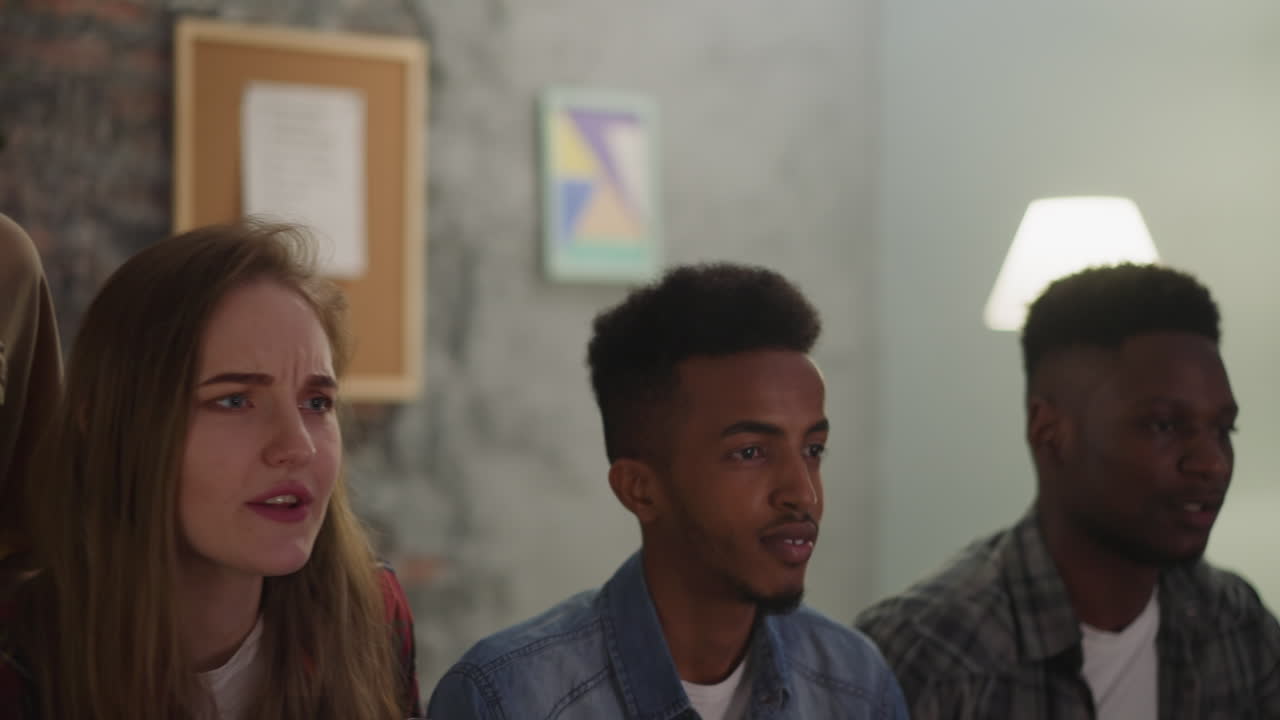 jóvenes nerviosos miran un complicado partido de fútbol por televisión