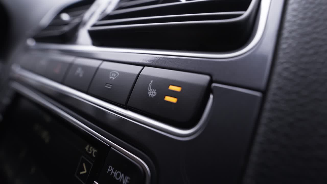 mujer ajustando el control de clima del coche y el calentador del asiento