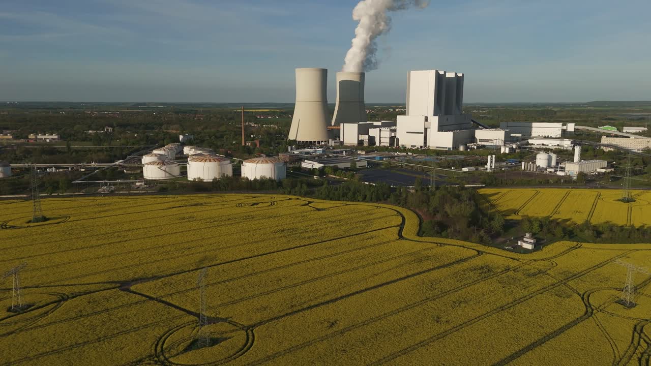 Drone shot of Lippendorf power plant near Leipzig, Germany. Rapeseed fields and industrial smokestacks create a striking contrast between nature and energy infrastructure.