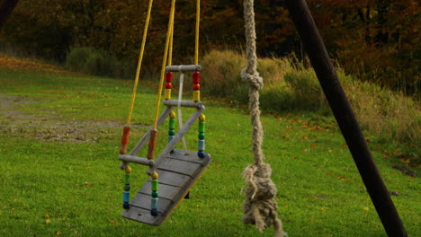 child's colored swing made of wood hanging on a construction moves during strong wind to the side during a sunny autumn day captured in beskids area 4k 60fps