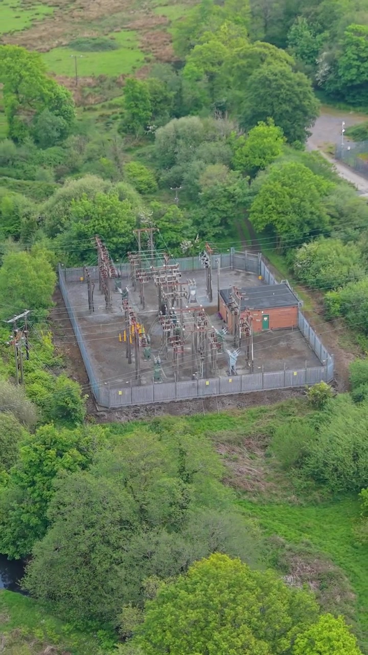 Video aereo verticale di una sottostazione elettrica ad alta tensione con trasformatori di potenza, interruttori automatici. Infrastruttura critica di una moderna rete elettrica, distribuzione di energia, ingegneria industriale