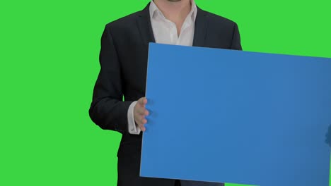 man in suit holding a blank board on a green screen, chroma key