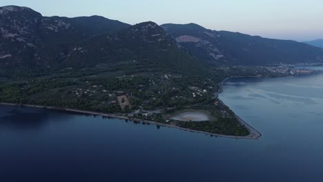 Coastline-road-winding-alongside-ocean,-mountainous-forest-landscape,-aerial-panned-footage