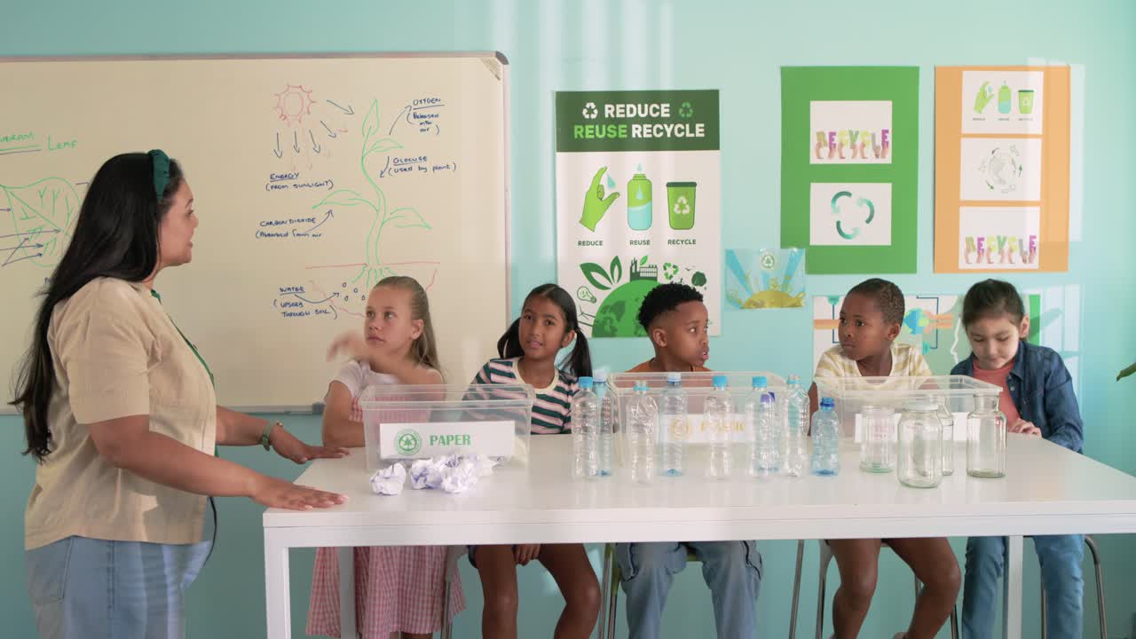 African American woman teacher tapping paper box, diverse kids at table raising hands for recycling