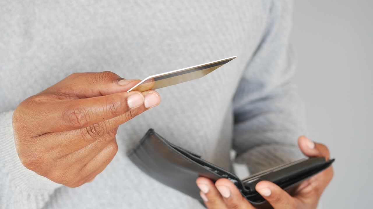 A man holds out a credit card in front of his wallet