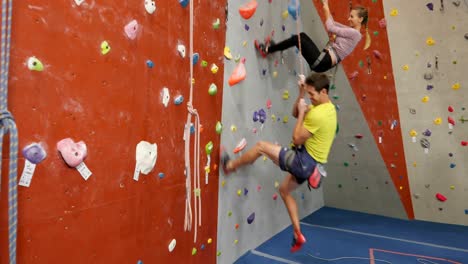 coach assisting woman in bouldering 4k