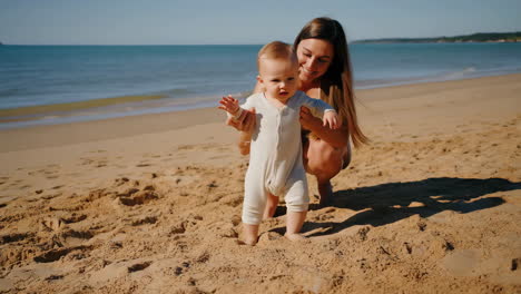 mother helping baby learn to walk on a beach